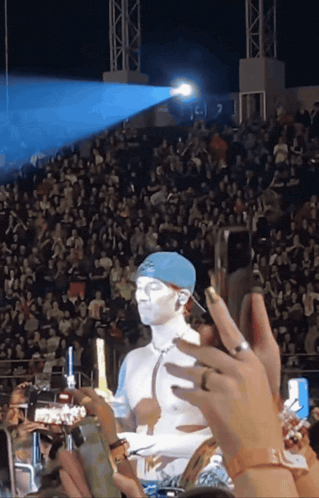 a man with white paint on his face is being photographed by a crowd