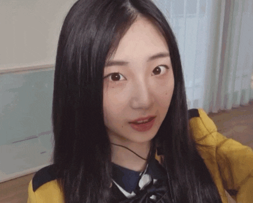 a girl with long black hair is wearing a yellow shirt