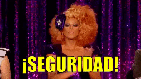 a drag queen is standing on a stage with a purple curtain behind her and says seguridad !