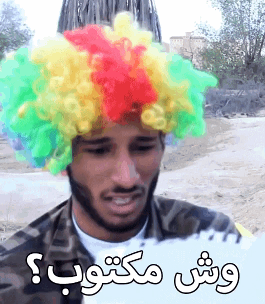 a man wearing a clown wig is holding a piece of paper with arabic writing