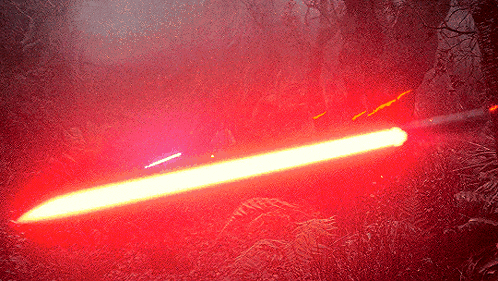 a red light beam is shining through a foggy forest