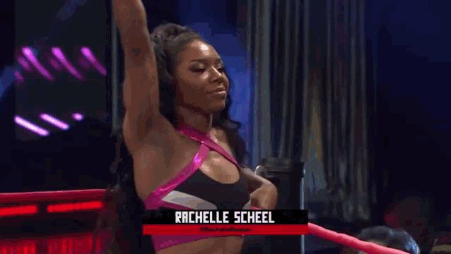a female wrestler named rachelle scheel is standing in a ring with her arm in the air