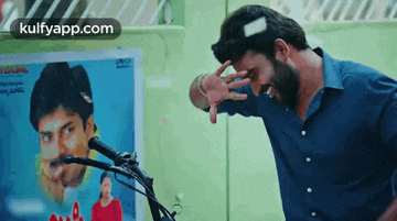 a man with a beard is standing in front of a picture of a man on a motorcycle .
