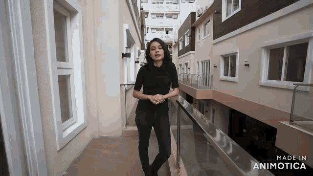 a woman in a black shirt is standing on a balcony in front of a building made in animotica