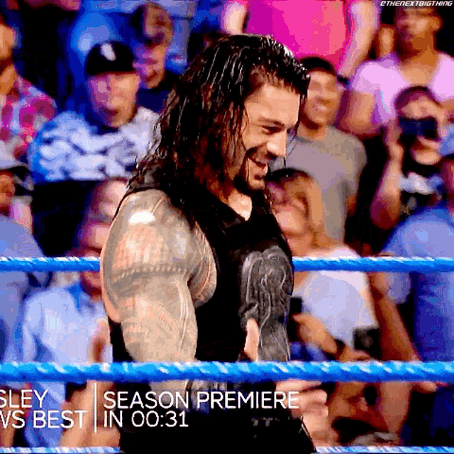 roman reigns is standing in a wrestling ring holding a belt ..