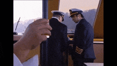 two men in military uniforms standing next to each other on a boat