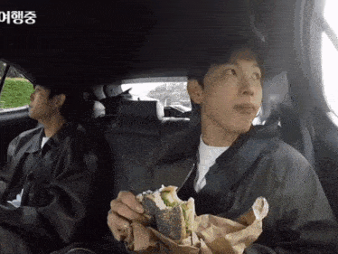 a man eating a sandwich in the back seat of a car with chinese writing on it
