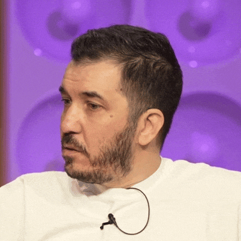 a man with a beard is wearing a white shirt with a microphone attached to it