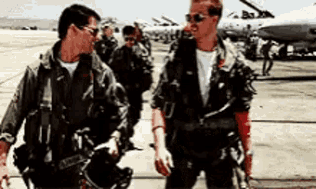 a group of men in military uniforms are walking on an airport runway .