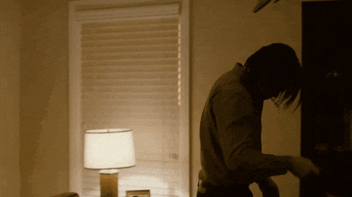 a man is standing in front of a window with blinds on it