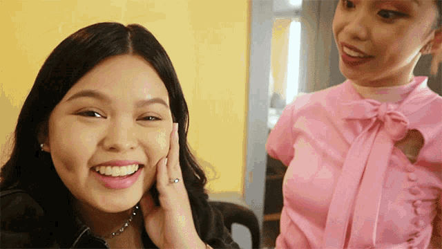 a woman with a ring on her finger is smiling next to another woman in a pink top