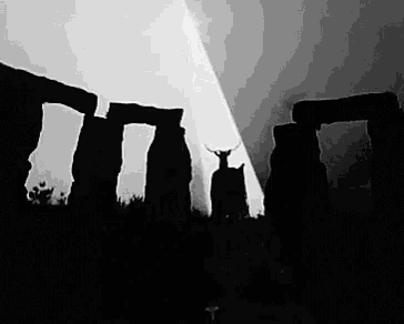 a black and white photo of a silhouette of a statue with horns