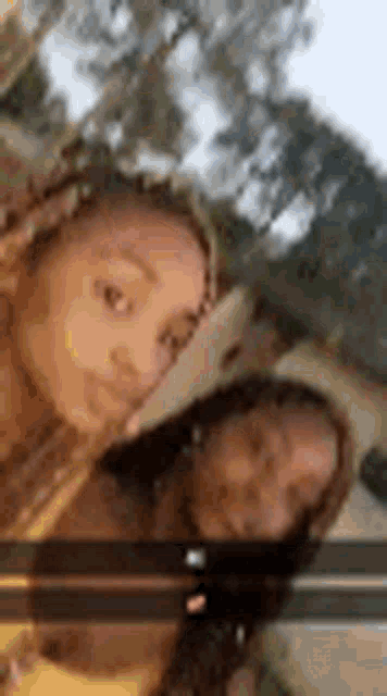 two girls are taking a selfie together in front of trees .