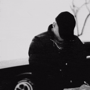 a black and white photo of a man wearing a baseball cap and jacket .