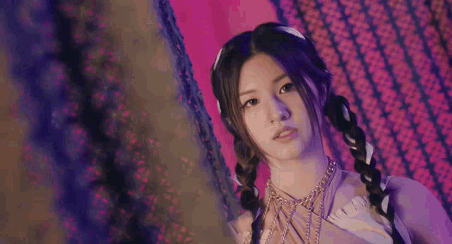 a girl with pigtails and a necklace on her neck looks at the camera