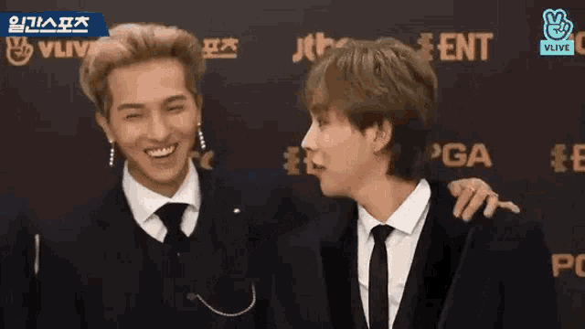 two men are standing next to each other on a red carpet .
