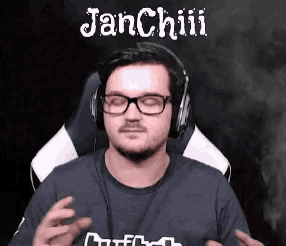 a man wearing headphones and glasses is sitting in a chair and making a face .