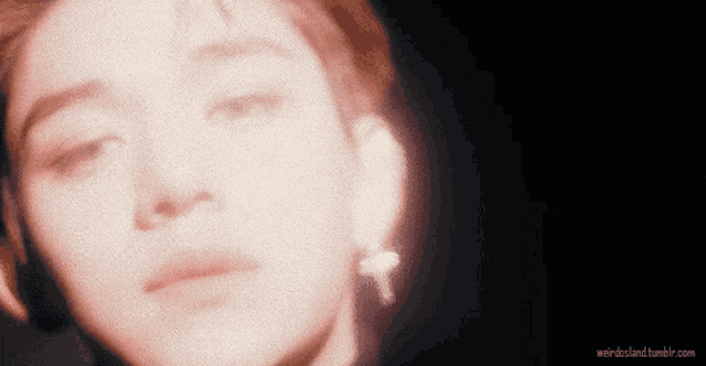 a close up of a person 's face with a cross earrings