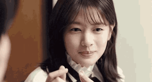 a close up of a young woman making a heart shape with her hands .