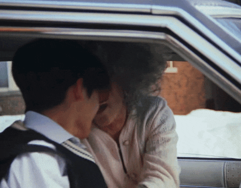 a man and a woman are sitting in a car and kissing