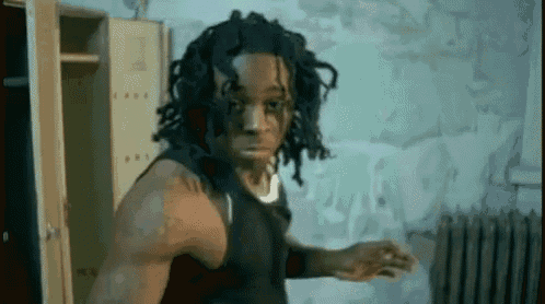 a man with dreadlocks is standing in a room with lockers and a radiator .
