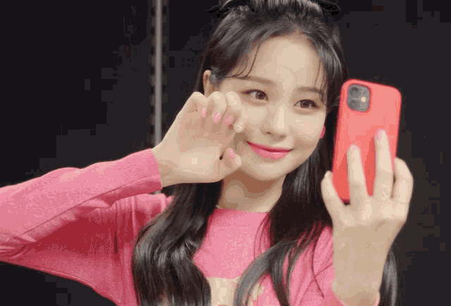 a girl in a pink sweater takes a selfie with her phone