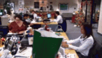 a woman sits at a desk in an office with a green folder that says ' christmas ' on it