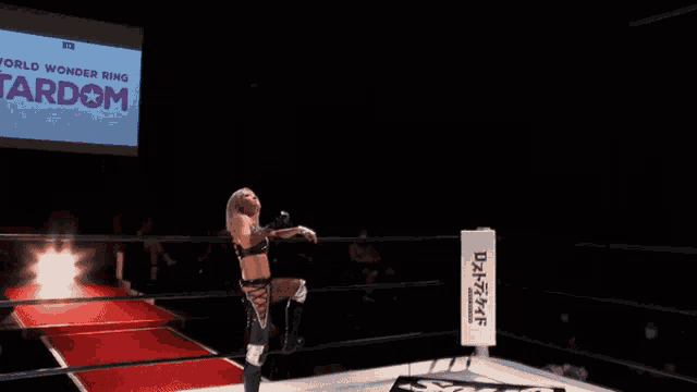 a woman stands in a wrestling ring in front of a large screen that says world wonder ring tardom