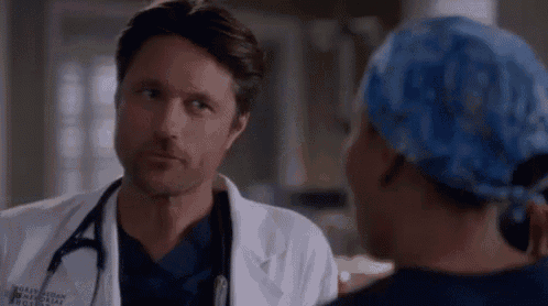a man in a lab coat and stethoscope is talking to a woman in a scrub hat .
