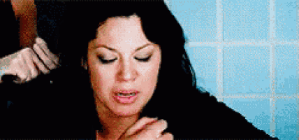 a woman is sitting in a bathroom with her eyes closed and a man is touching her hair .