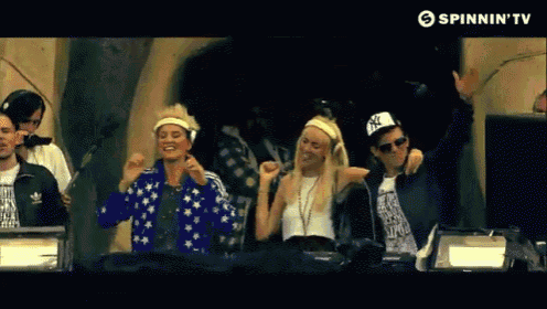 a group of people are dancing in front of a spinnin ' tv screen