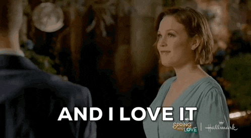 a woman in a blue dress is talking to a man in a suit and the words `` and i love it '' are visible .