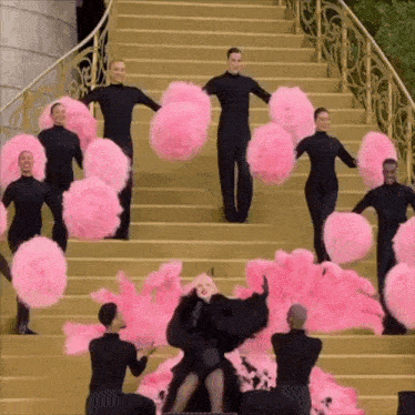a group of people are standing on a set of stairs with pink pom poms