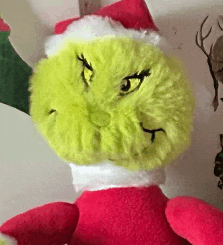 a grinch stuffed animal with a santa hat on