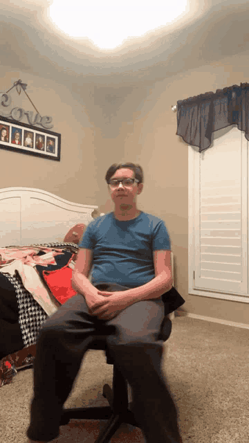 a boy is sitting in a chair in front of a love sign on the wall