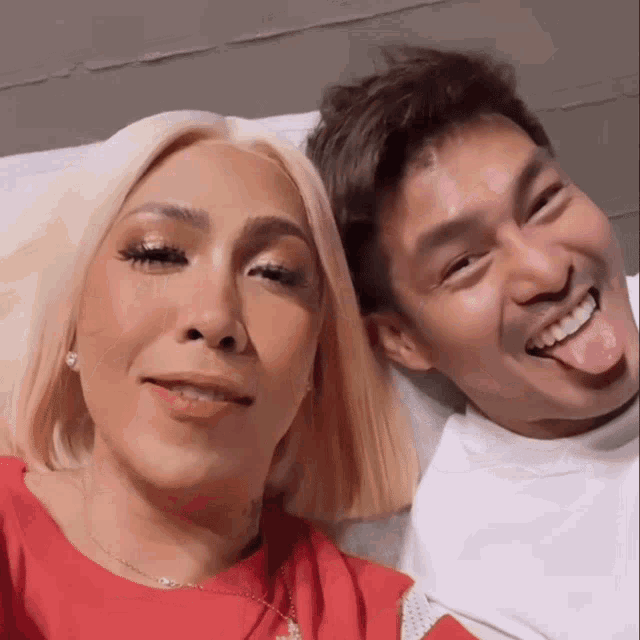 a man sticking his tongue out next to a woman in a red shirt