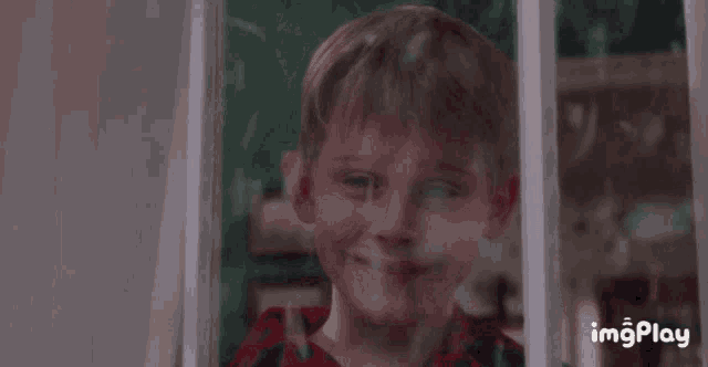 a young boy is smiling while looking out of a window with imgplay written on the bottom