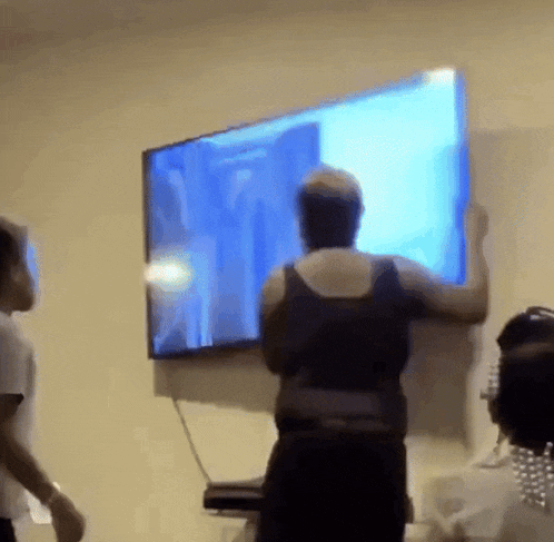 a woman in a black tank top is standing in front of a flat screen tv