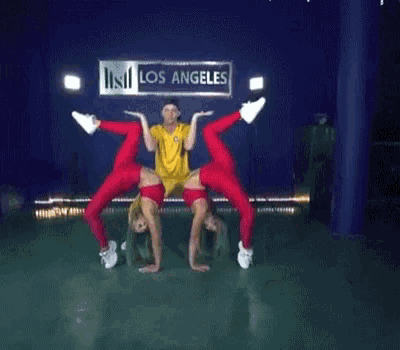 a man in a yellow shirt is doing a handstand in front of a los angeles sign