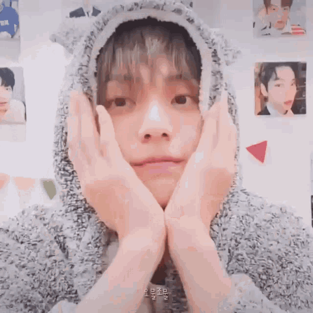 a close up of a person wearing a hoodie making a face with their hands .