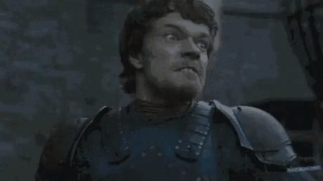 a man in armor is making a funny face with his mouth open in a dark room .