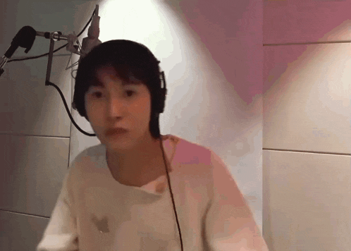 a woman wearing headphones and a white shirt looks at the camera