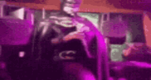 a blurred image of a man in a superhero costume holding a purple cape .