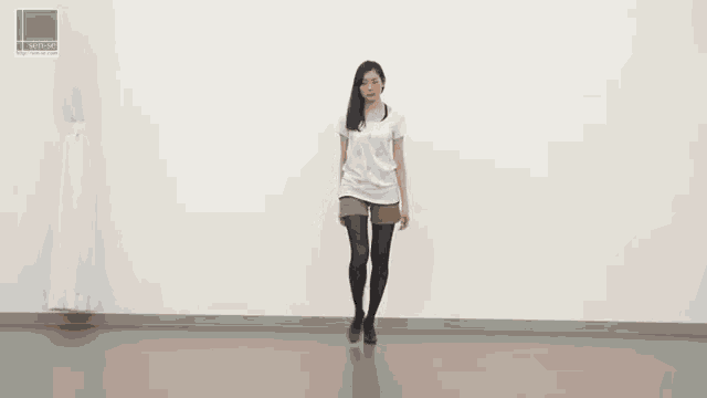 a woman in a white shirt and shorts is walking in a room with a green sign that says softtop on it