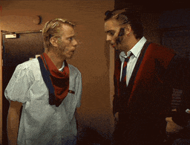 two men standing next to each other with one wearing a scarf