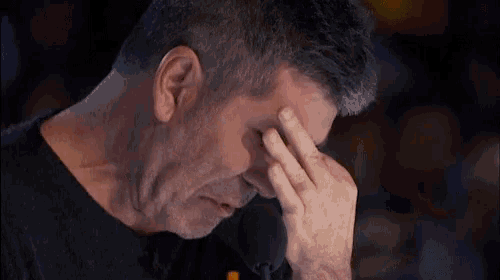 a man covering his face with his hand while looking down