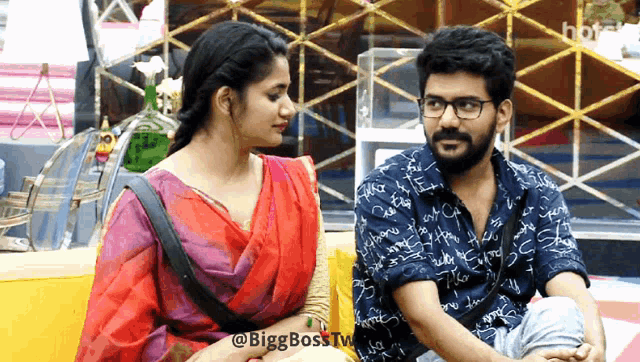 a man and a woman are sitting next to each other with the words bigg boss tv visible