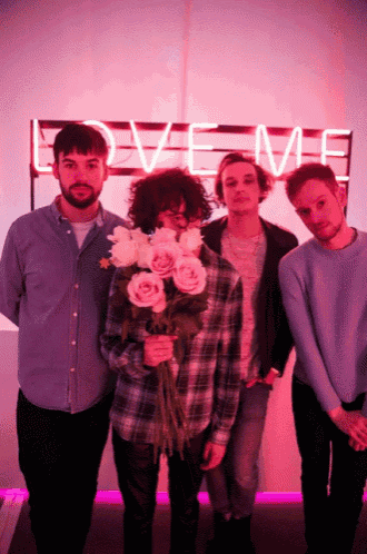 a group of men standing in front of a love me sign