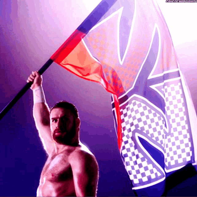 a shirtless wrestler is holding up a flag with the letter s on it