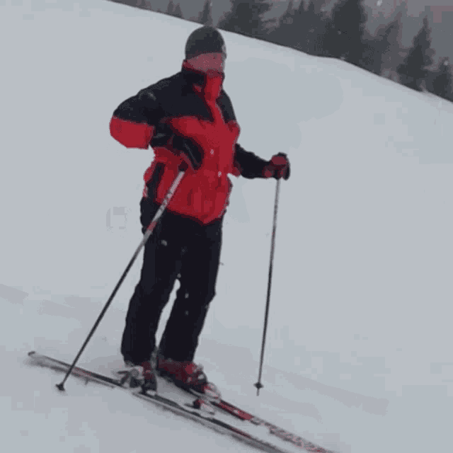 a person skiing down a snow covered slope wearing a red jacket